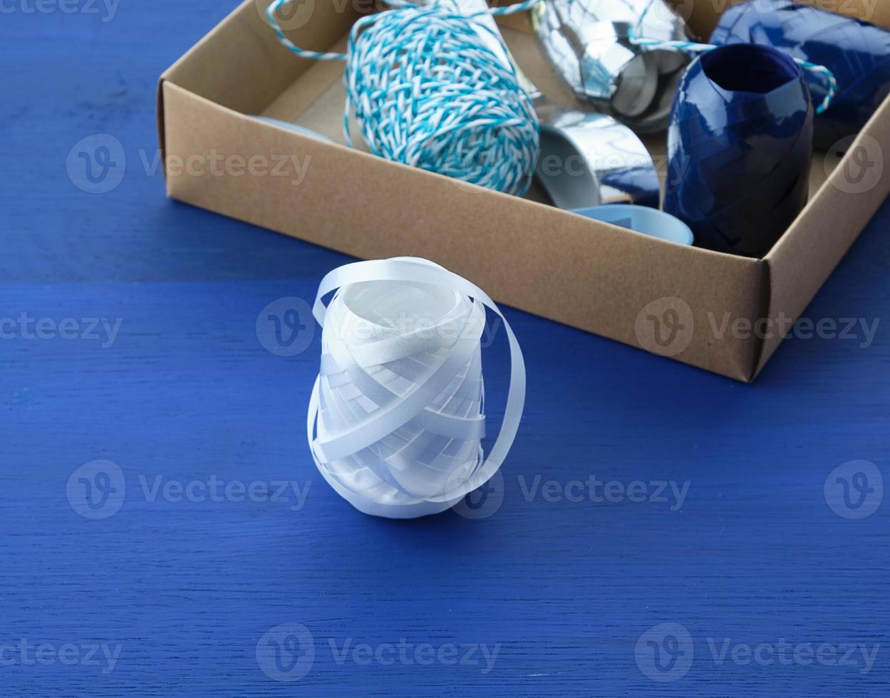 brown cardboard box with a set of decor ribbons for wrapping gifts on a dark blue background photo