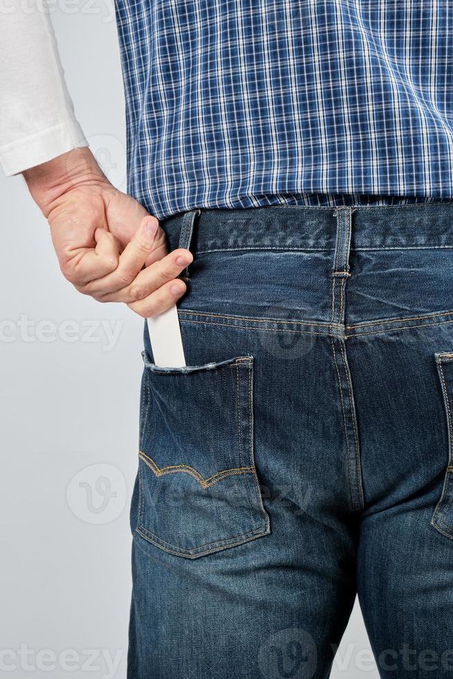 man puts an empty white paper business card in his back jeans pocket photo