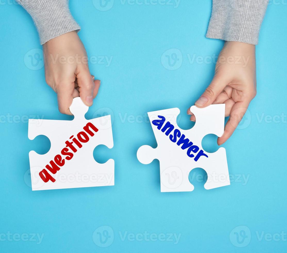 female hands holding big paper white puzzles with a question and answer inscription photo