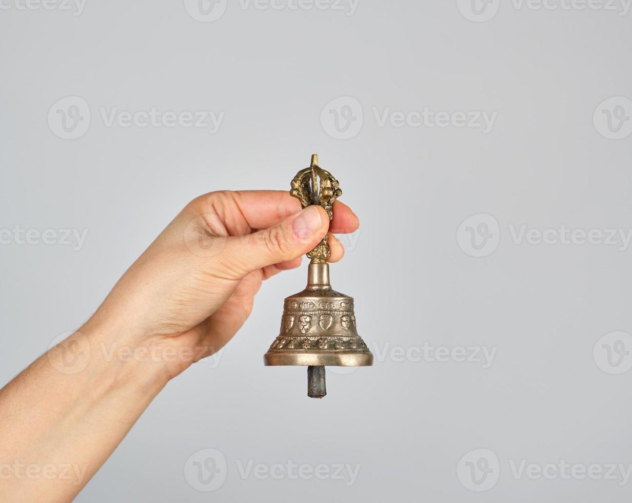 female hand holding a bronze bell for alternative medicine photo