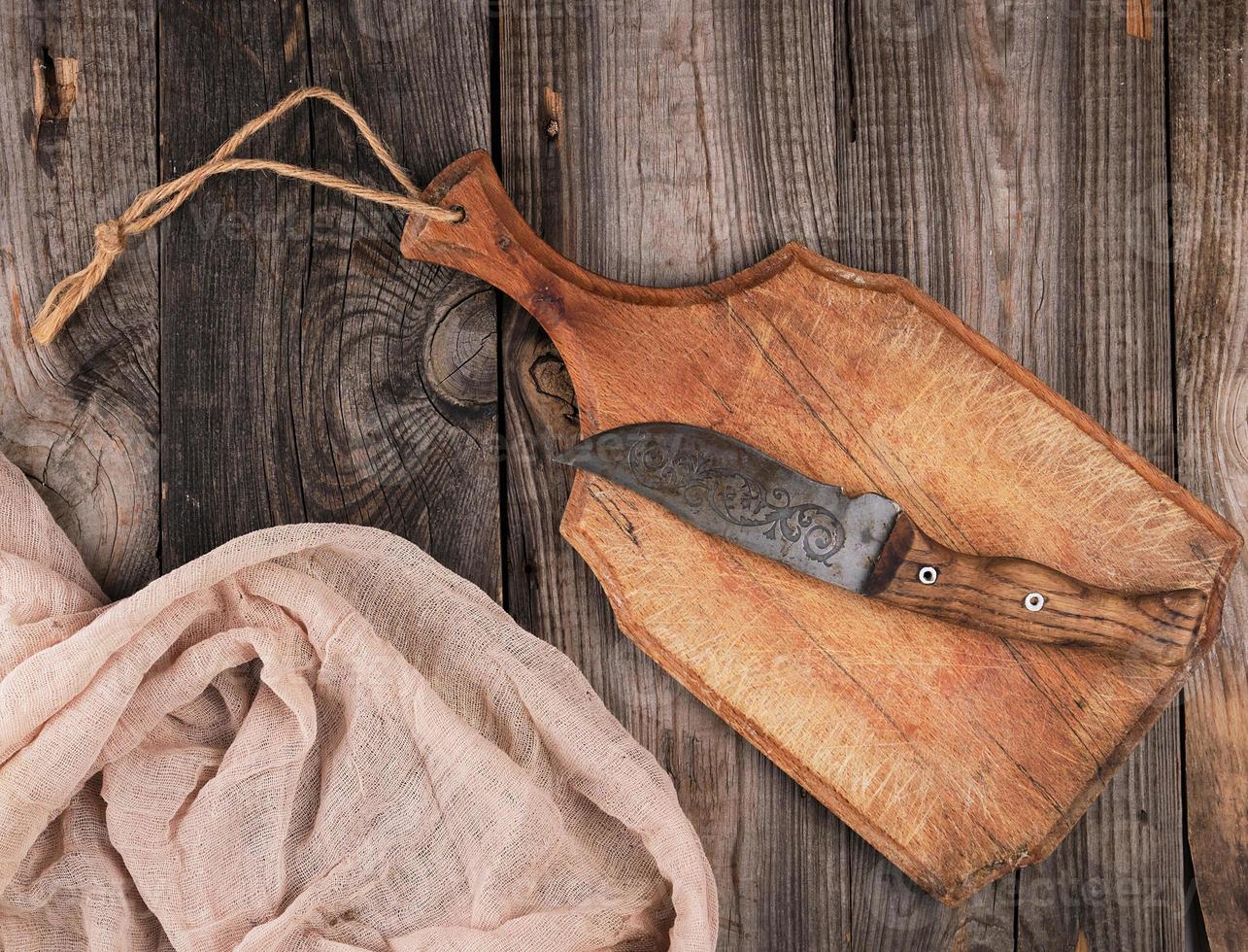 empty old brown wooden cutting board with handle and gray textile napkin photo