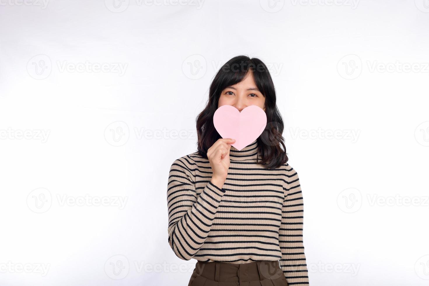 Beautiful young asian woman holding a paper heart while standing against white background. Beautiful young asian woman with paper heart. photo