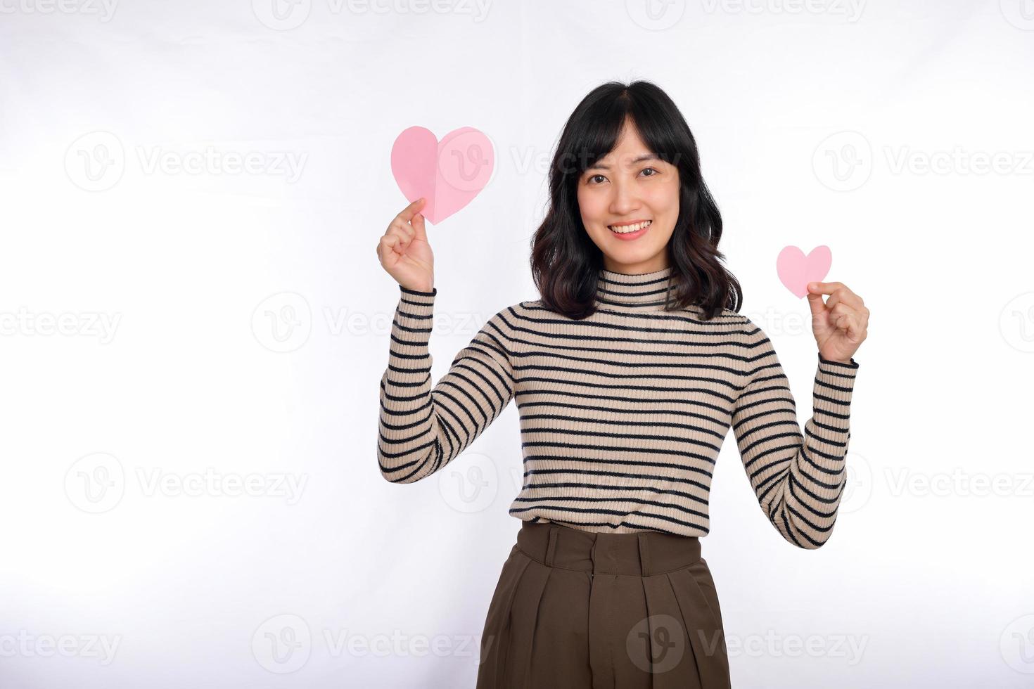 Beautiful young asian woman holding a paper heart while standing against white background. Beautiful young asian woman with paper heart. photo