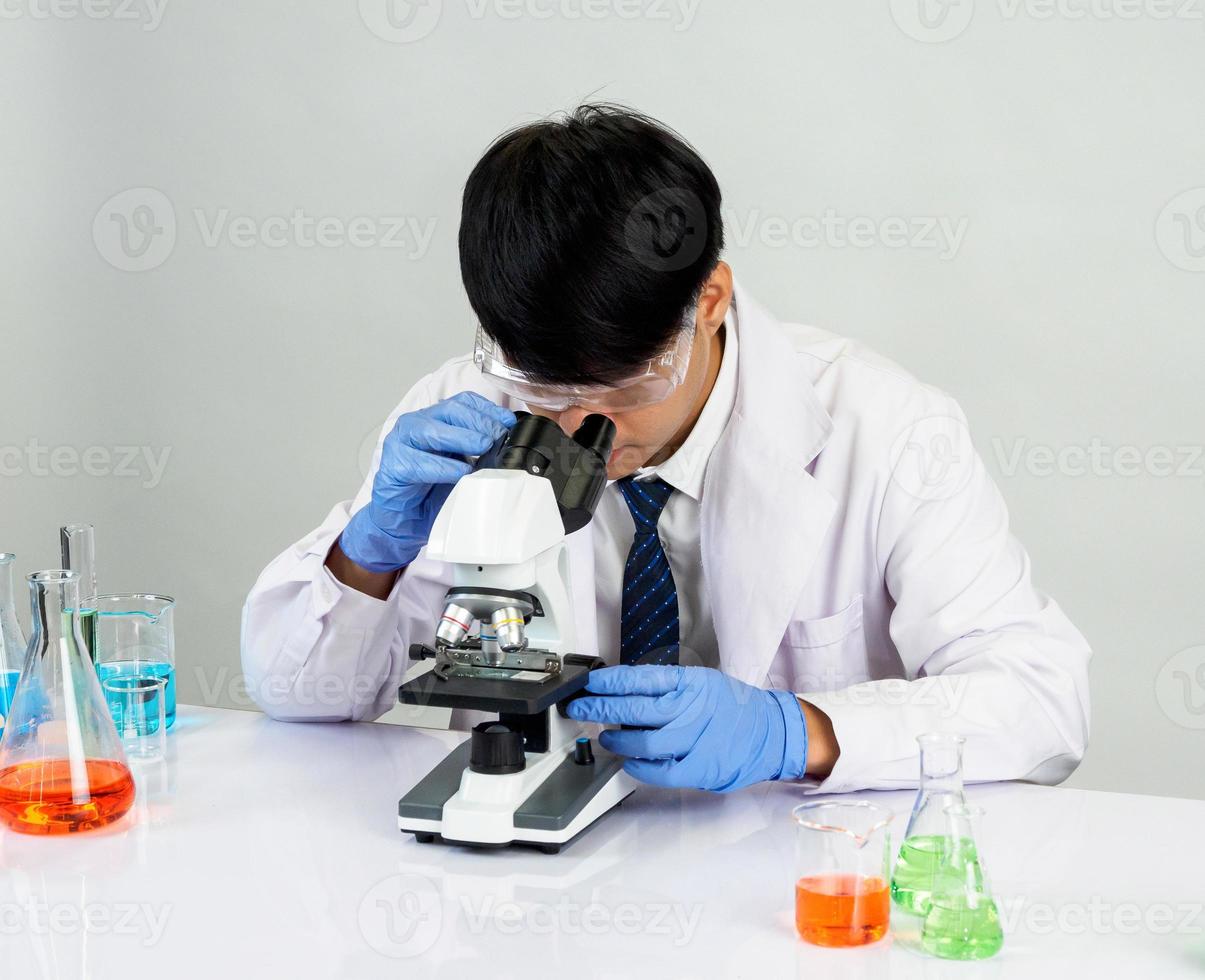 Asian male student scientist in reagent mixing laboratory In a science research laboratory with test tubes of various sizes and microscopes. on the table in  laboratory chemistry lab white background. photo