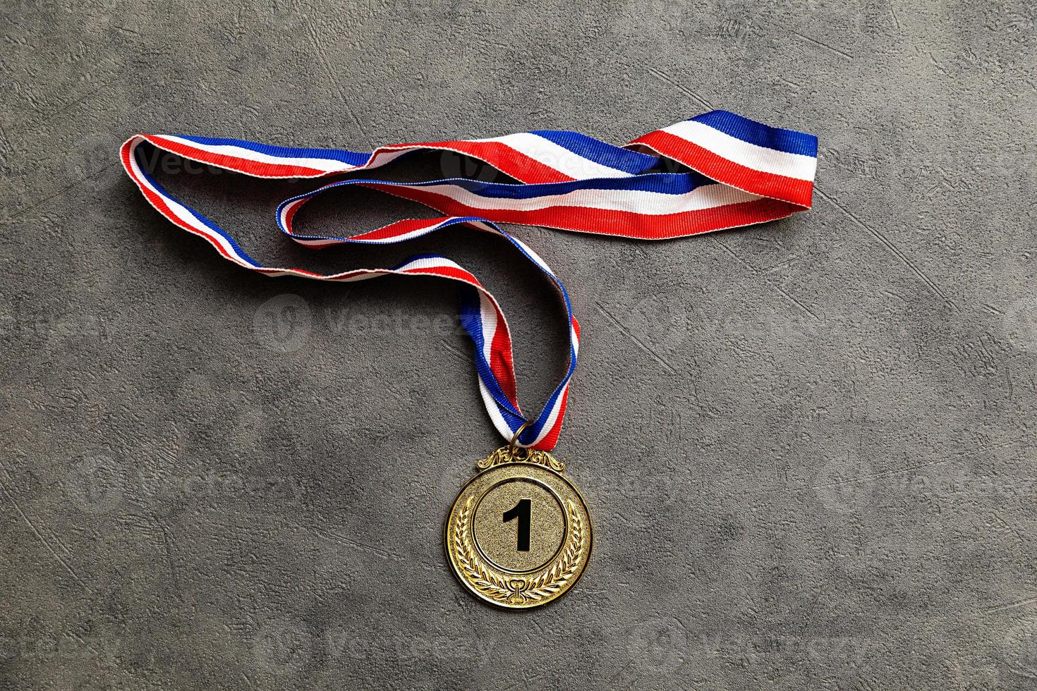 Simply flat lay design winner or champion gold trophy medal on concrete stone grey background. Victory first place of competition. Winning or success concept. Top view flat lay copy space. photo