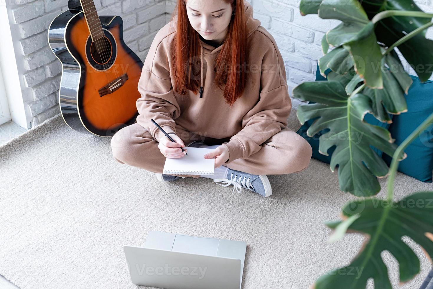 Young woman learning to play guitar at home photo