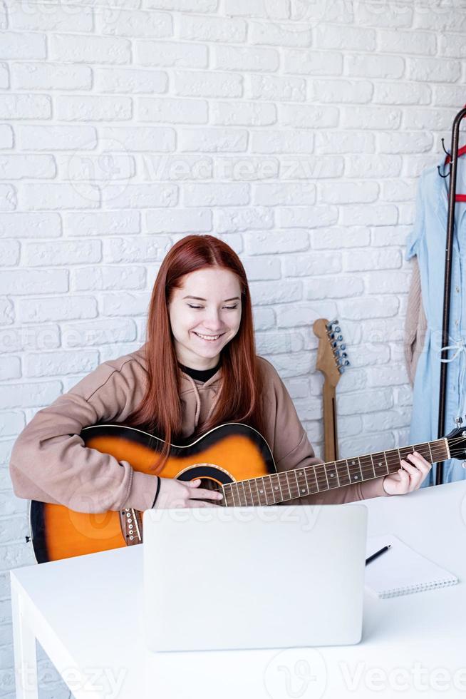 joven mujer aprendizaje a jugar guitarra a hogar foto