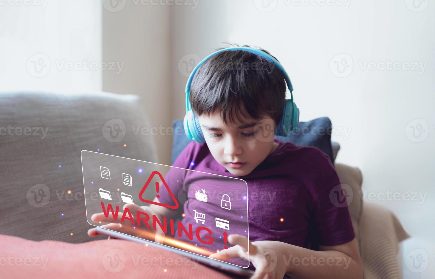School kid doing homework on tablet and receiving warning triangle sign for error notification display cyber attack,Danger Caution Warning Concept for Protecting Kid while using internet photo