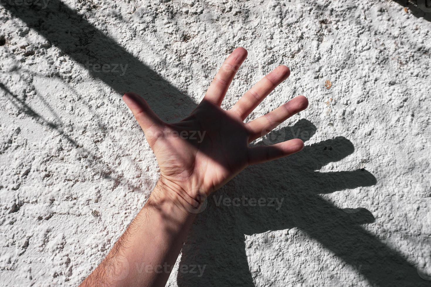 hand on the white wall gesturing with shadows photo
