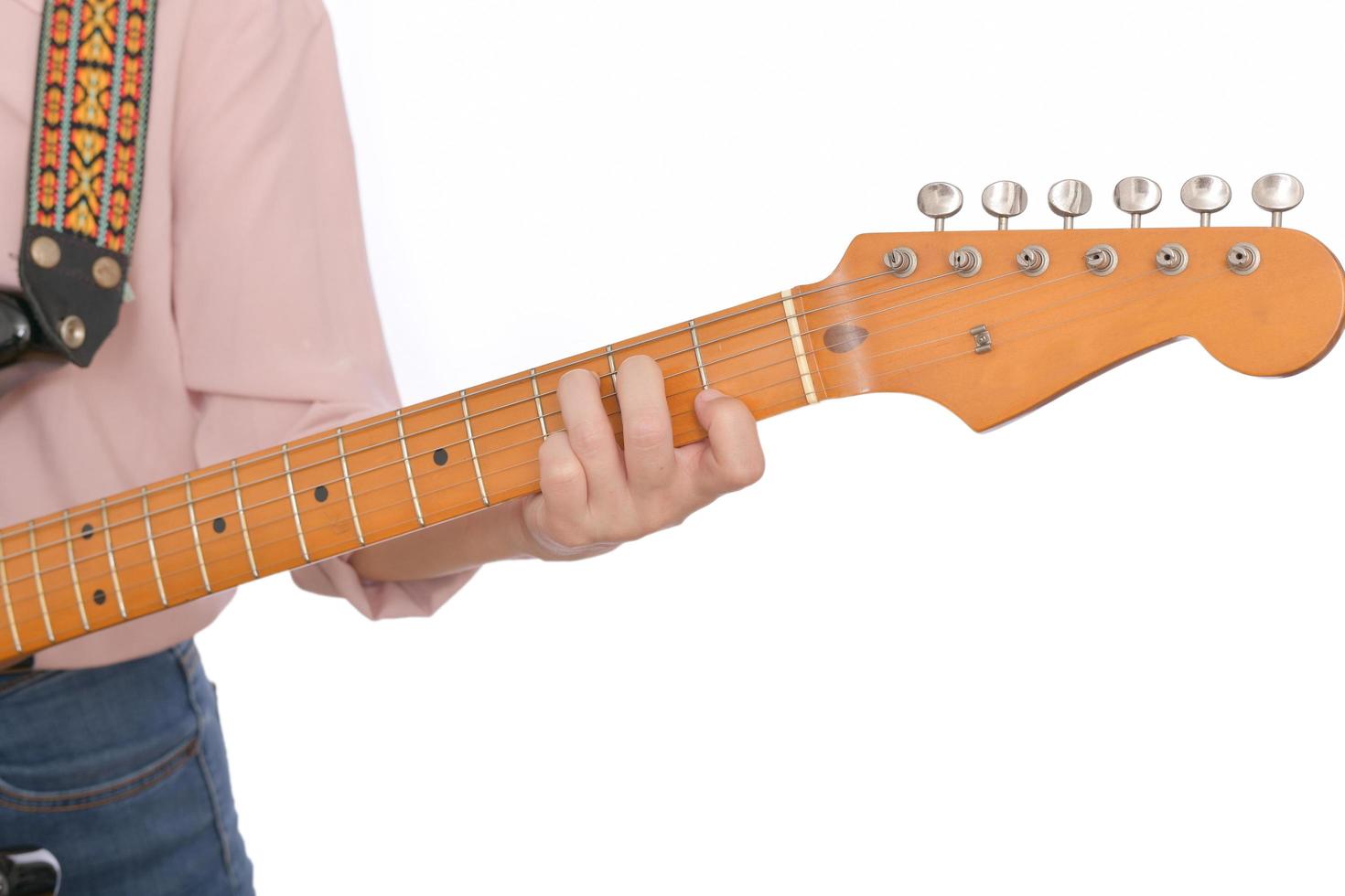 Close up of woman hand with casual clothing holding guitar neck and play some chord isolated on white background photo