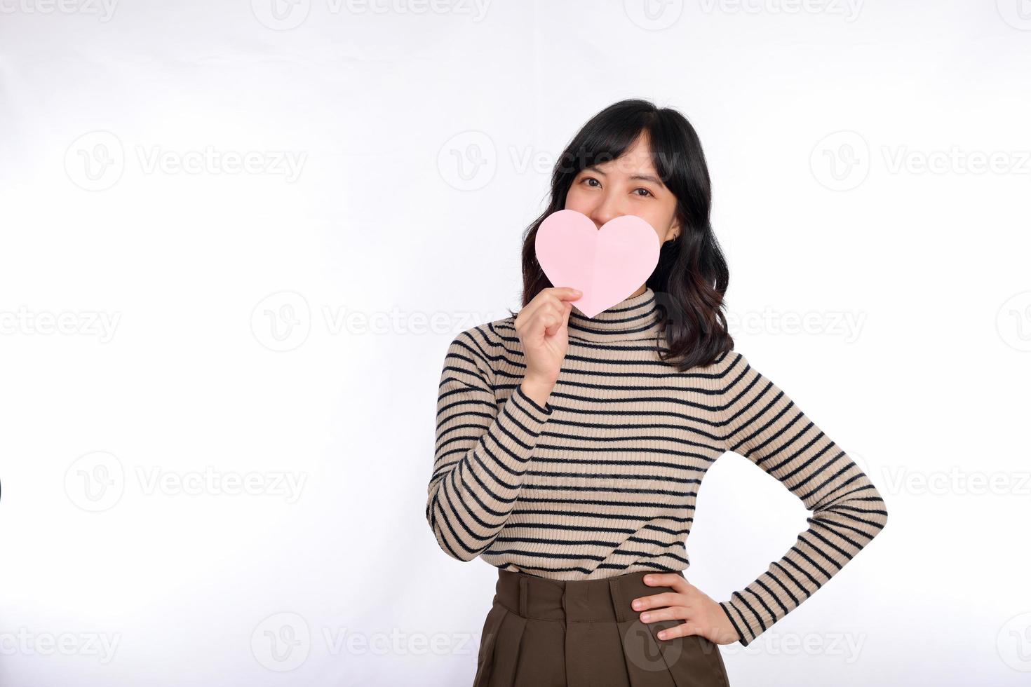 Beautiful young asian woman holding a paper heart while standing against white background. Beautiful young asian woman with paper heart. photo