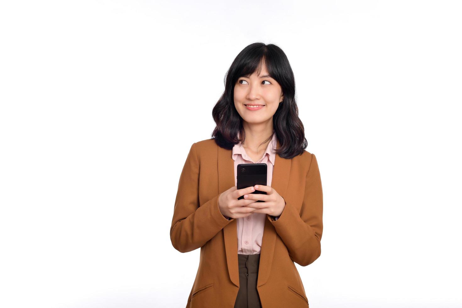 People and technology concept. Smiling asian girl using smartphone, texting on mobile phone, standing against white background photo