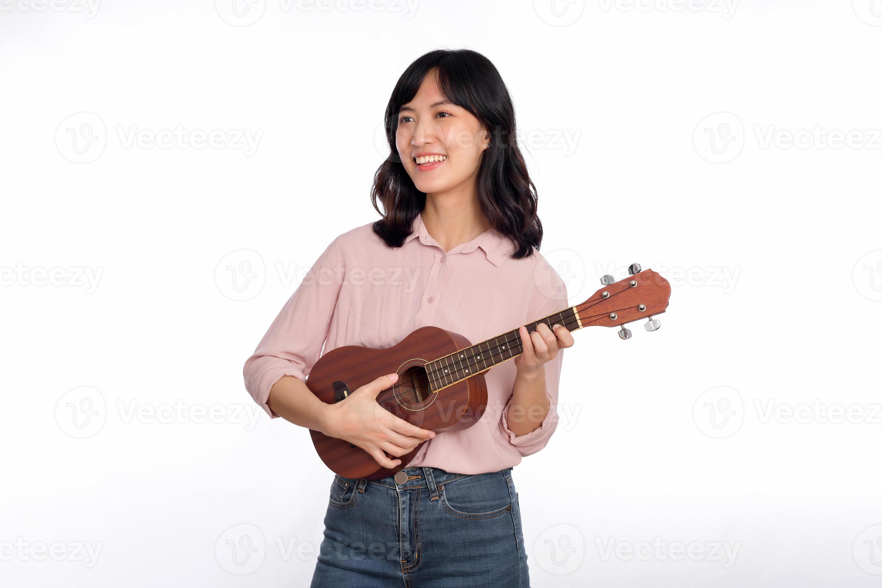 Happy young asian woman with casual clothing playing ukulele