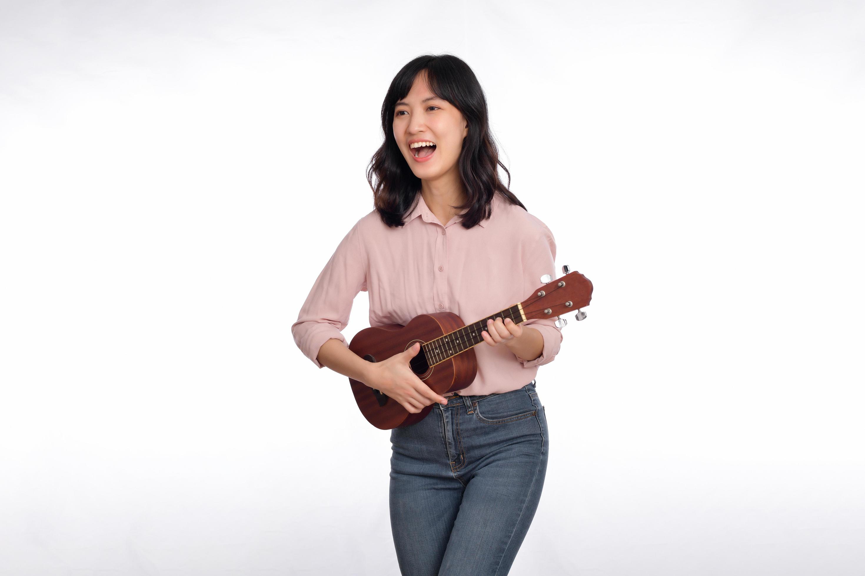 Happy young asian woman with casual clothing playing ukulele isolated on  white background 19765023 Stock Photo at Vecteezy