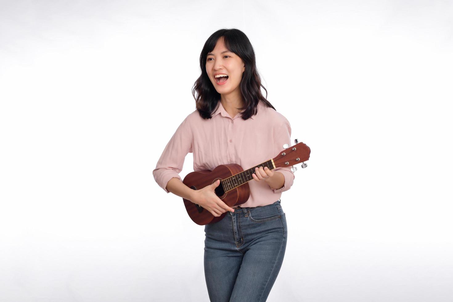 Happy young asian woman with casual clothing playing ukulele isolated on white background photo