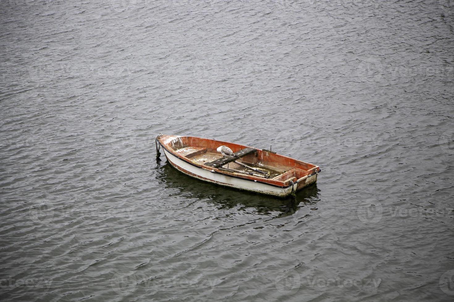 Vertical shot of an old wooden boat in a small lake on a cloudy