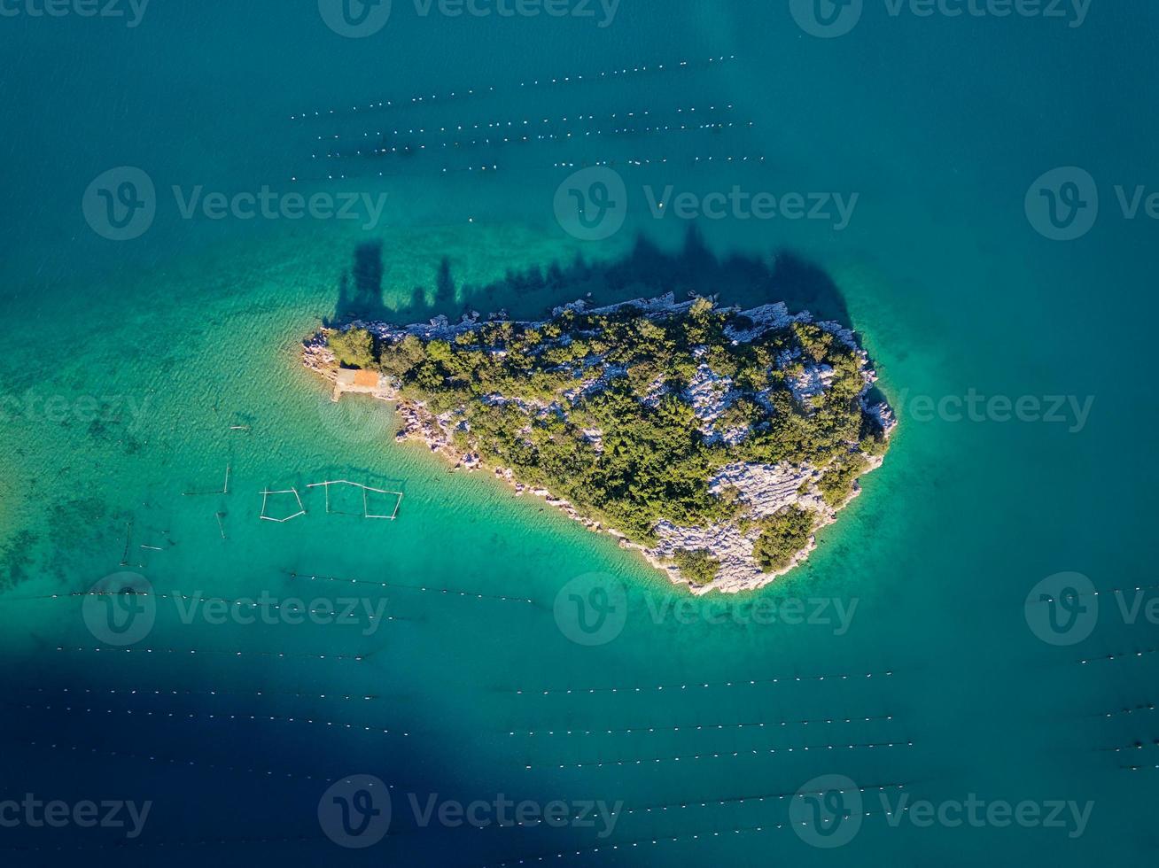 Aerial drone view of a small island in the bay of Mali Ston located on Peljesac peninsula. Oyster farms in the turquoise sea water. Unique mix of freshwater and seawater. photo