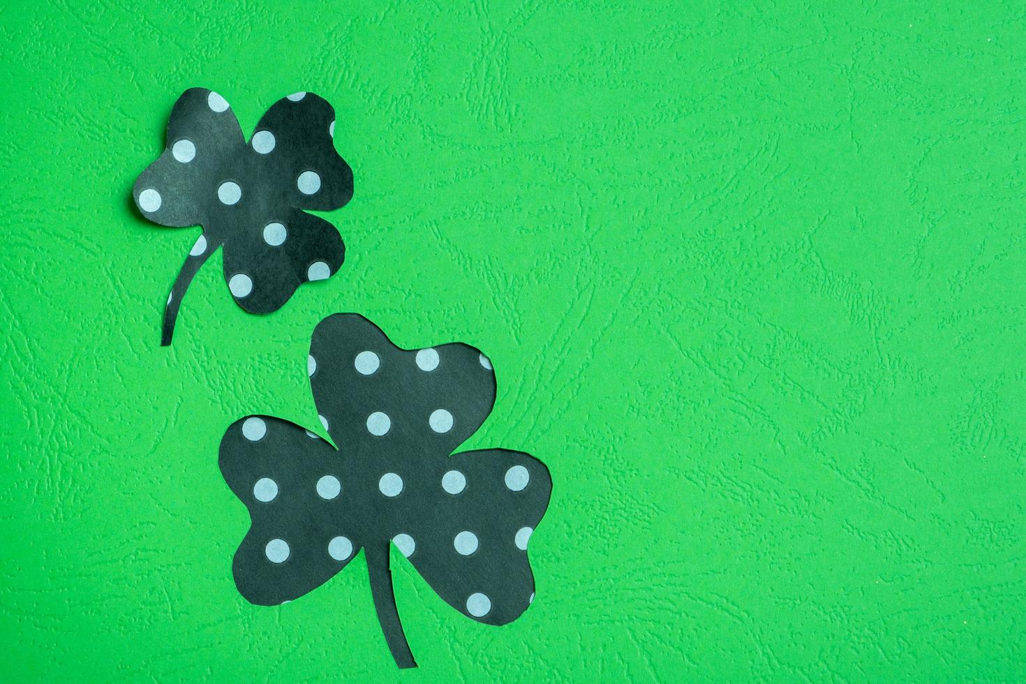 St. Patrick's Day minimalistic concept. Paper clover leaves on colored background with copy space photo