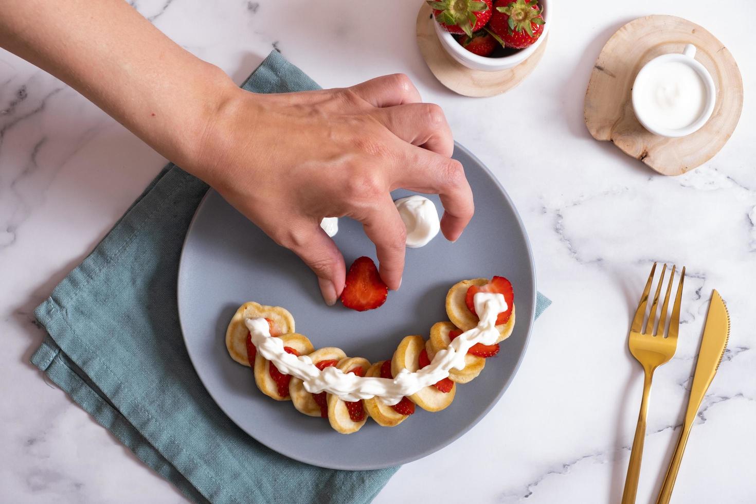 Small pancakes with strawberries in the original serving in the form of a smiley face. Top view. Flat lay photo