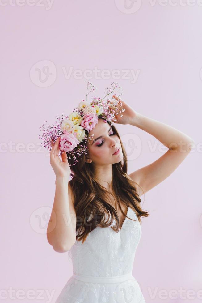 joven novia en blanco vestir con flor guirnalda en su cabeza posando en el estudio foto