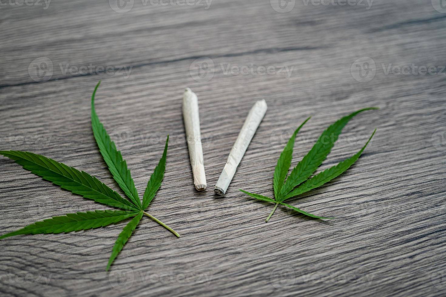 Joints with marijuana leaves on woodden table background. photo