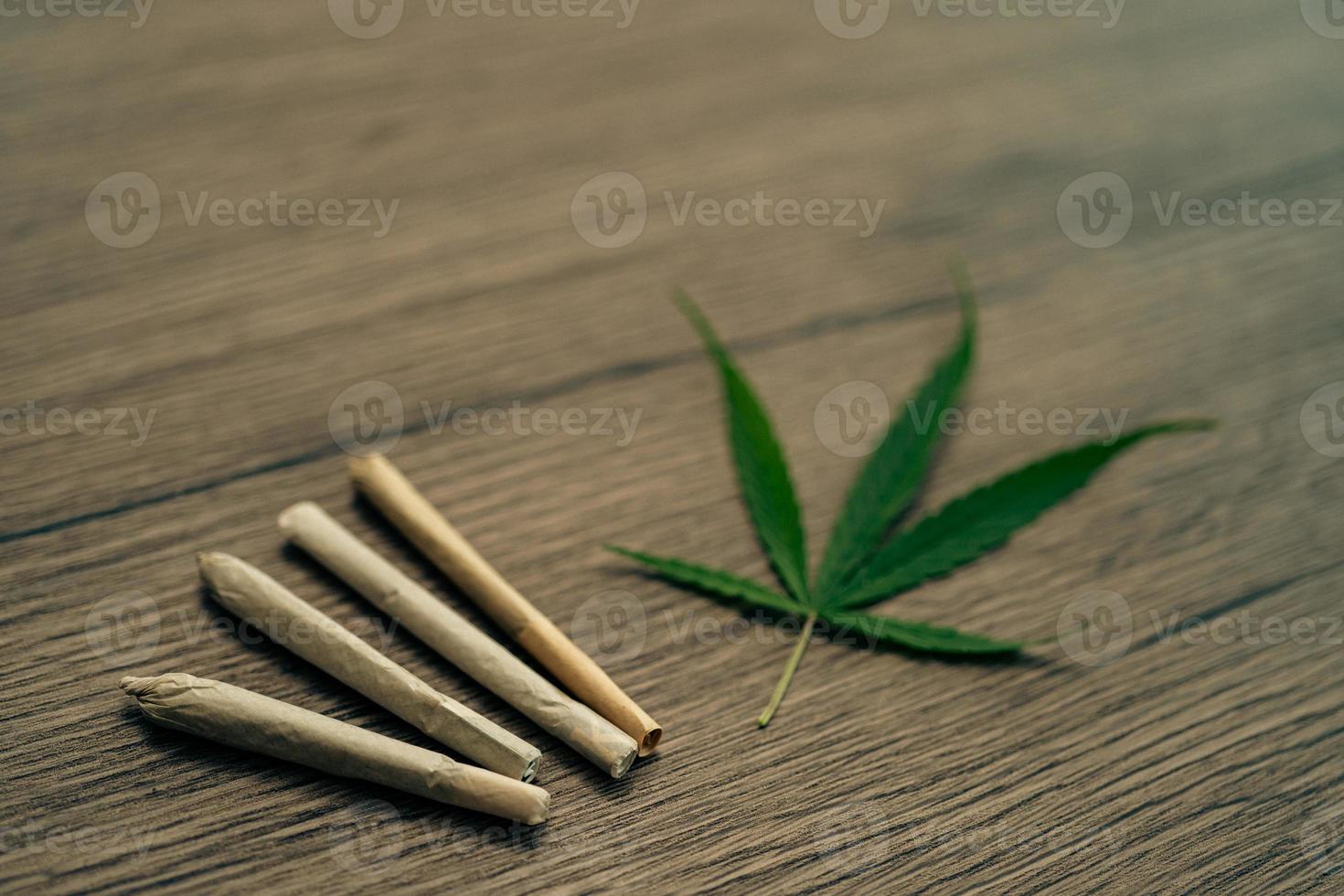 Joints with marijuana leaves on woodden table background. photo