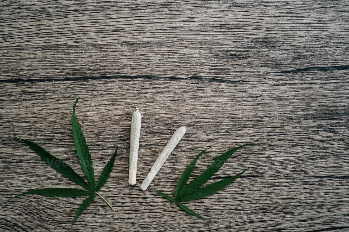 Joints with marijuana leaves on woodden table background. photo