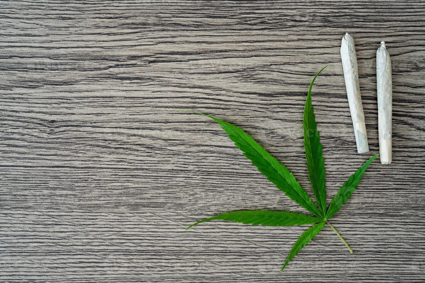 Joints with marijuana leaves on woodden table background. photo