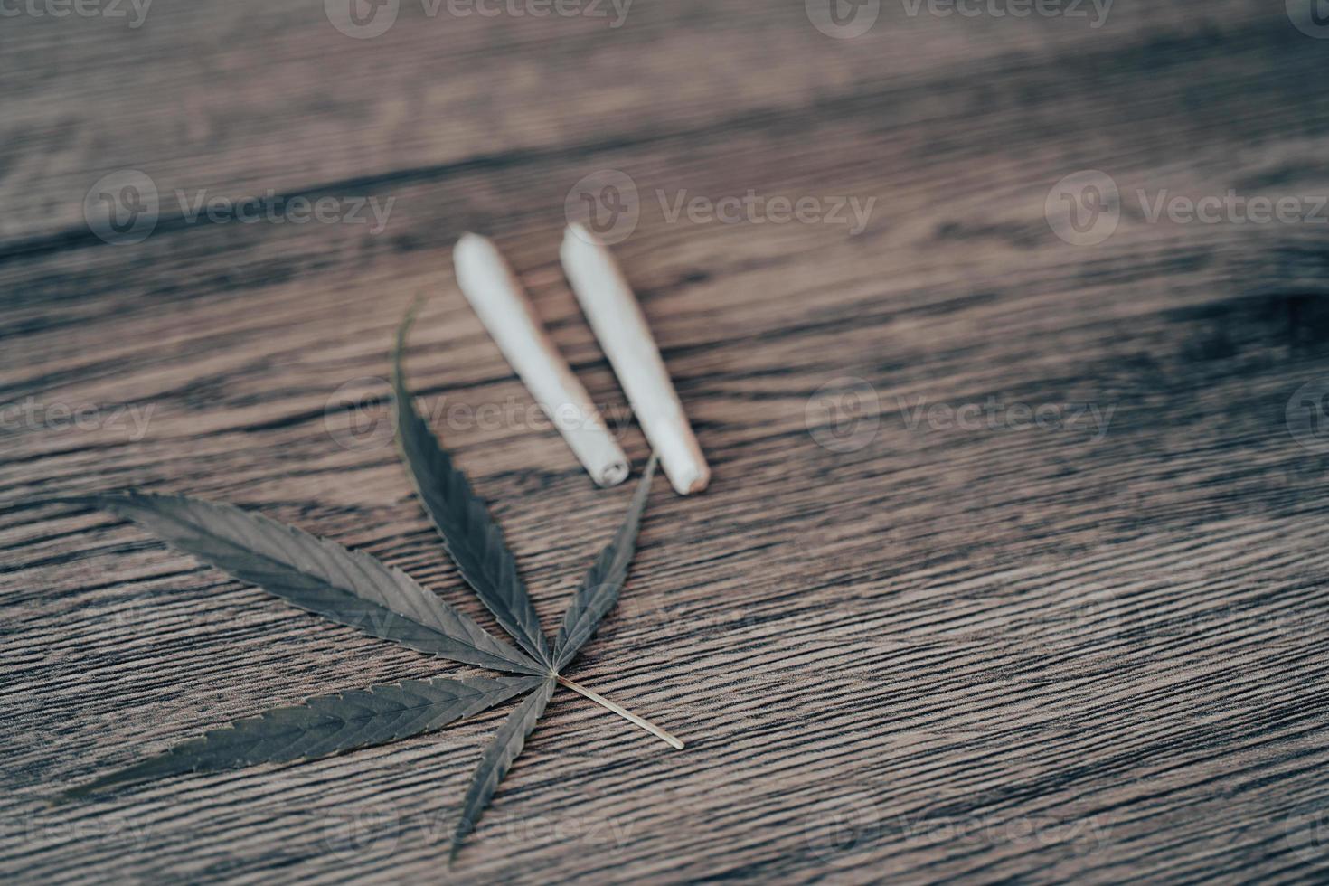Joints with marijuana leaves on woodden table background. photo