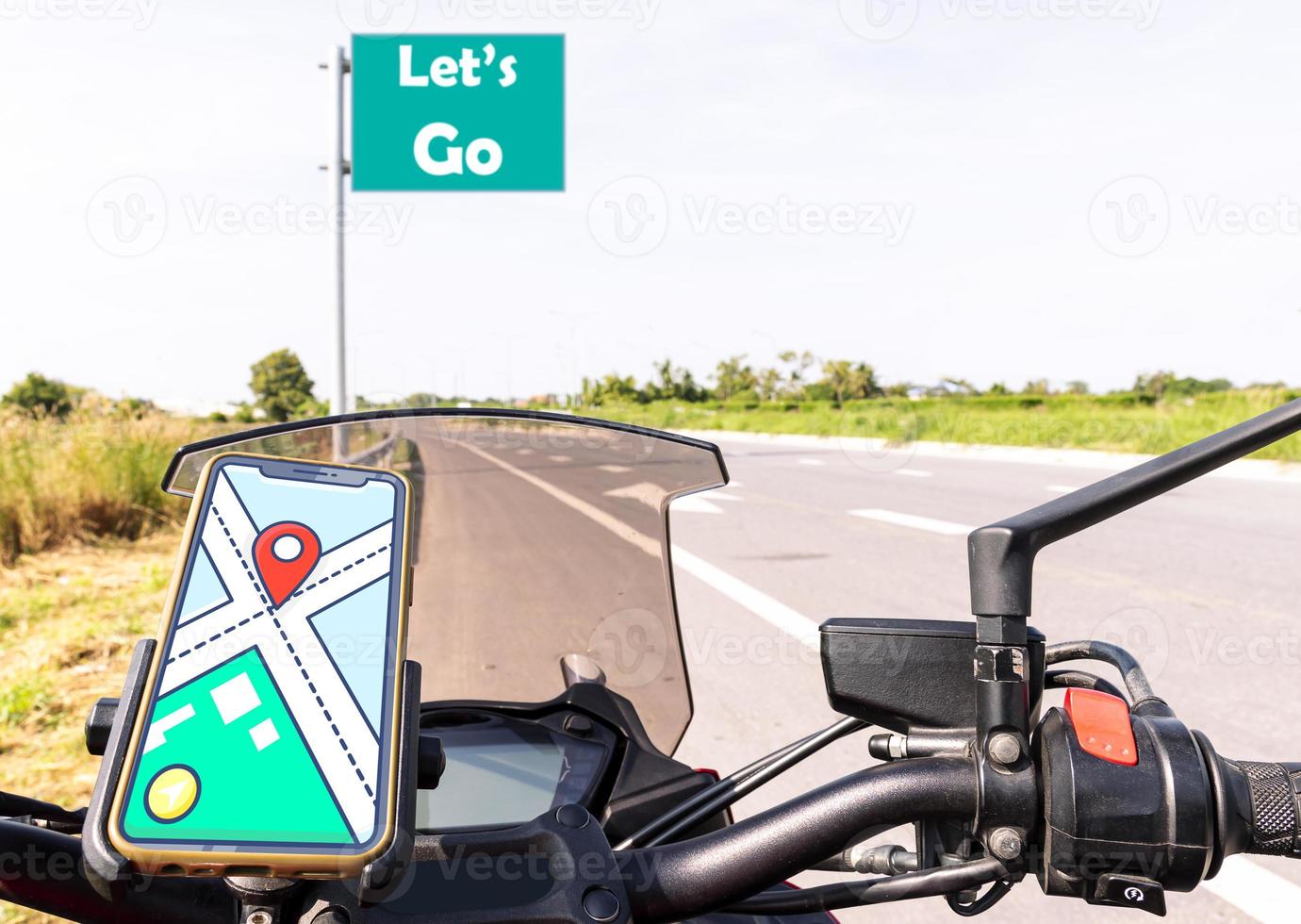 Navigate map on display smartphone on handle bar motorcycle with message Let's Go on green road sign and highway road view photo
