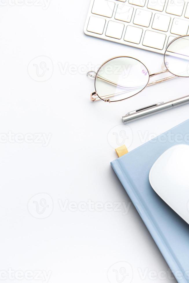 Keyboard, computer mouse and notebook with pen on white office desk photo