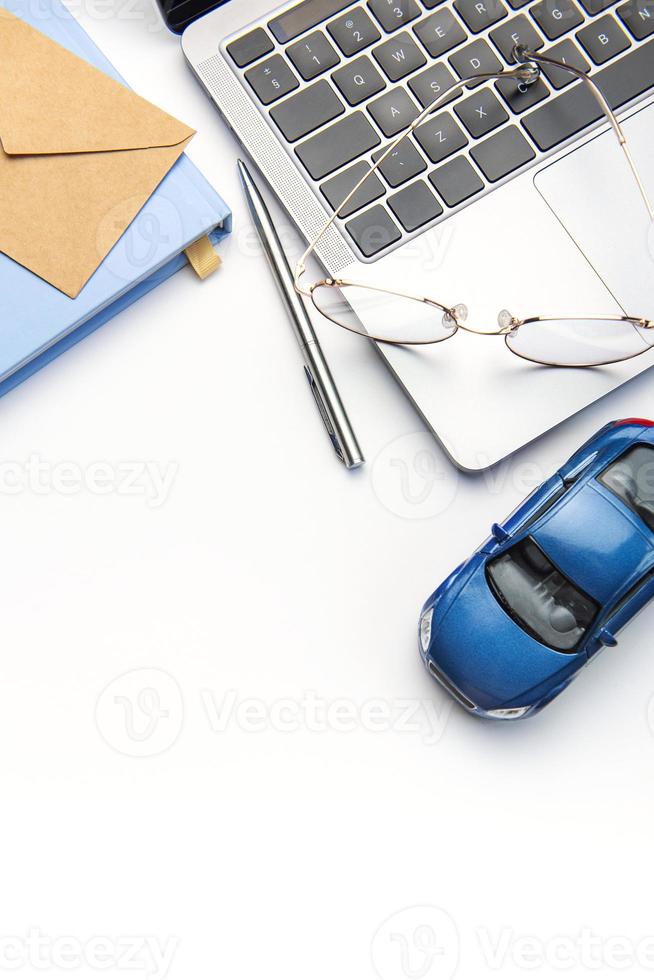 Modern white office desk table with laptop, notebook, toy car and other supplies. photo