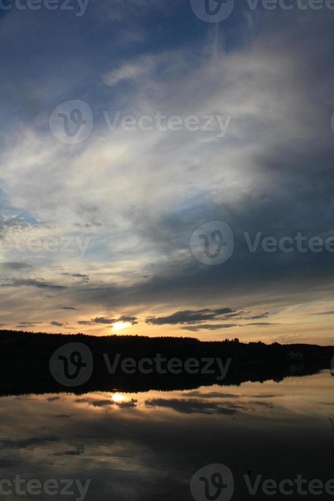 Sunset cloudy sky reflected in forest lake landscape photo