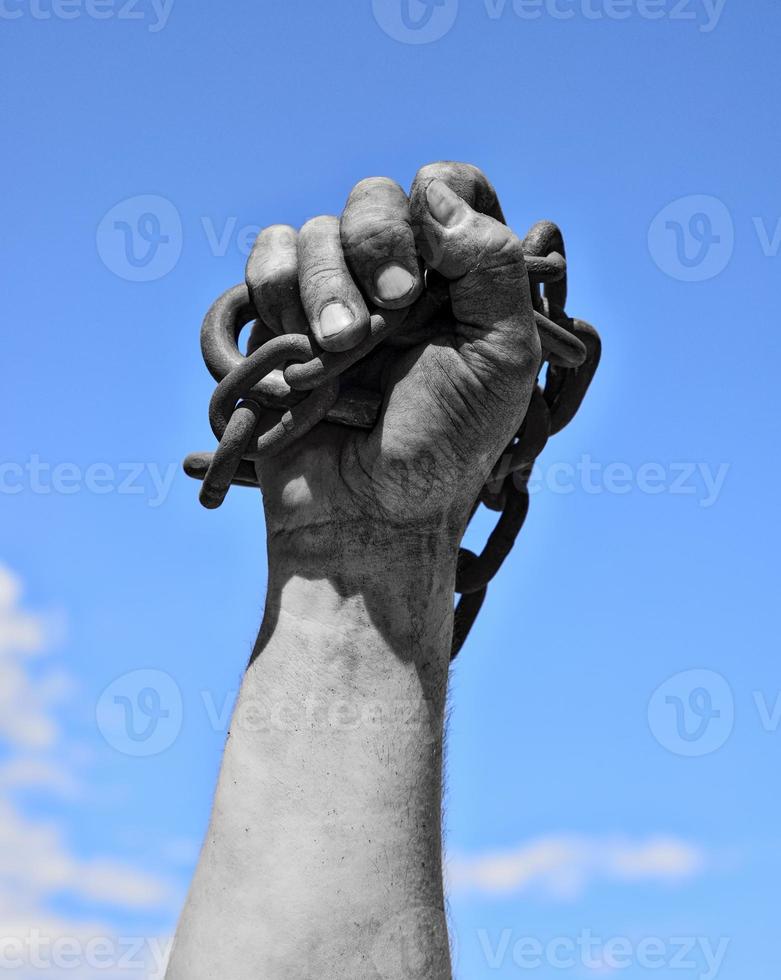 Dirty hand with chain against the blue sky photo