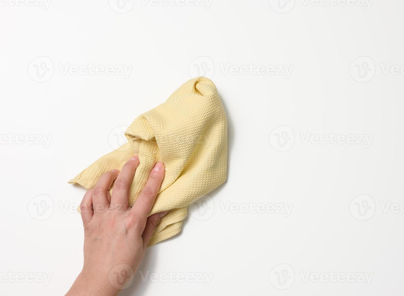 female hand holding a yellow rag on a white background photo