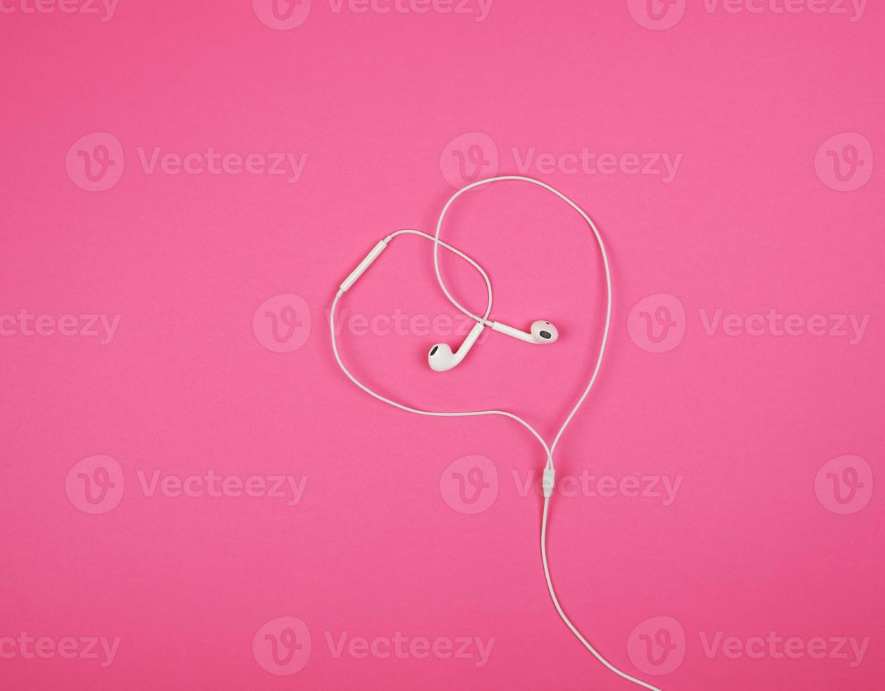 white headphones with a cable on a pink background photo
