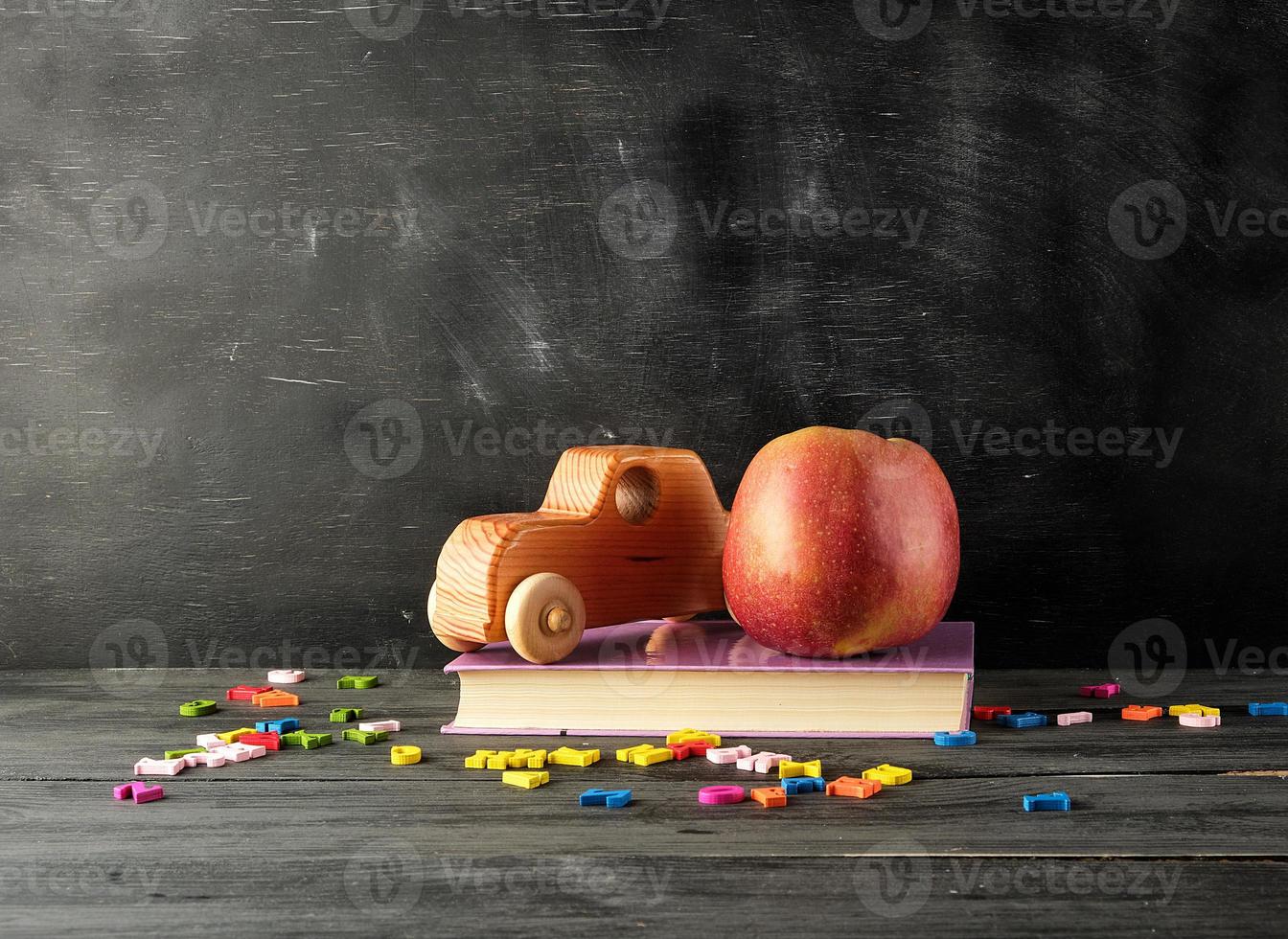 ripe red apple,  ancient toy car stand on a book photo