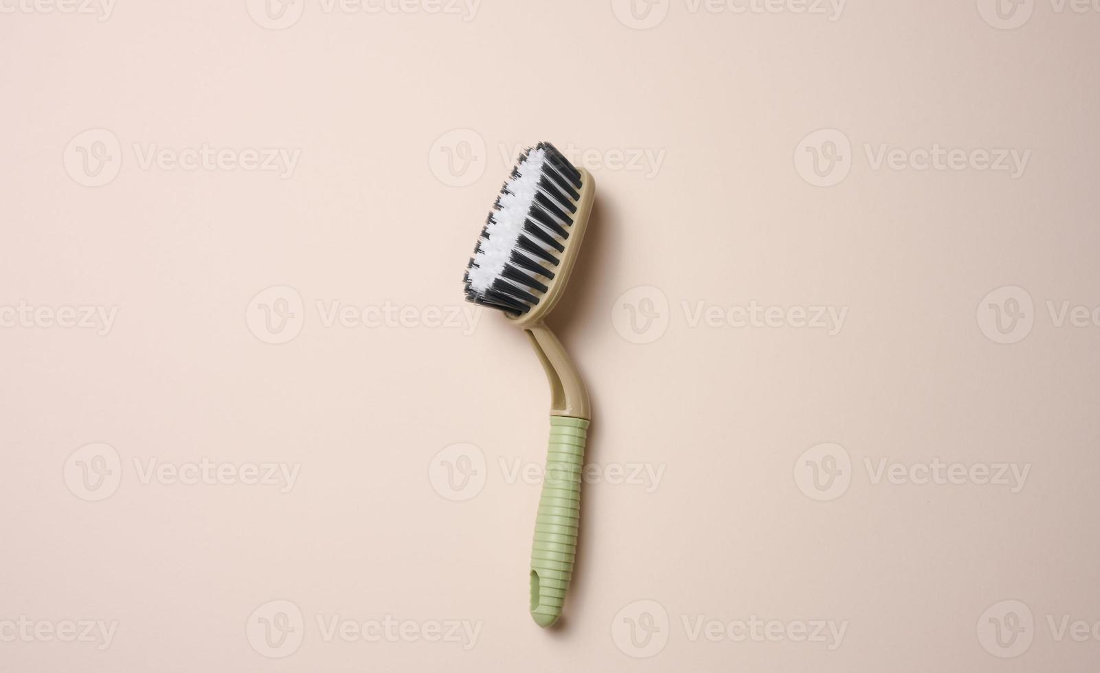 plastic brush with handle for cleaning the house on beige background, top view photo