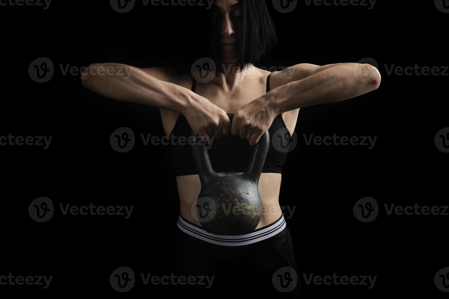 beautiful athletic girl with black hair raised with two hands a metal weight photo