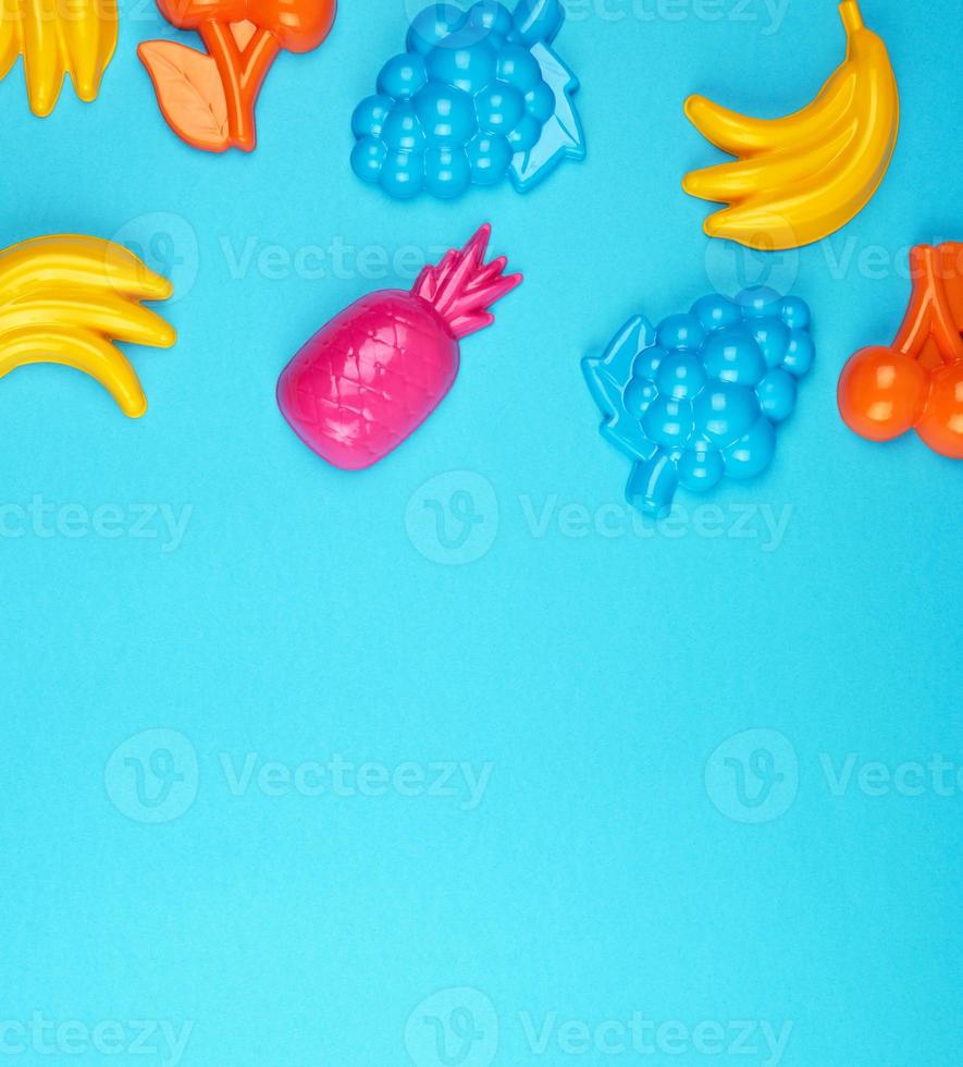 multicolored plastic toys fruits on a blue  background photo