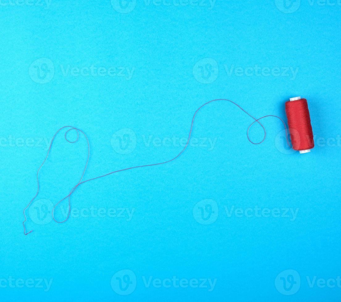 spool of red threads on a blue background photo