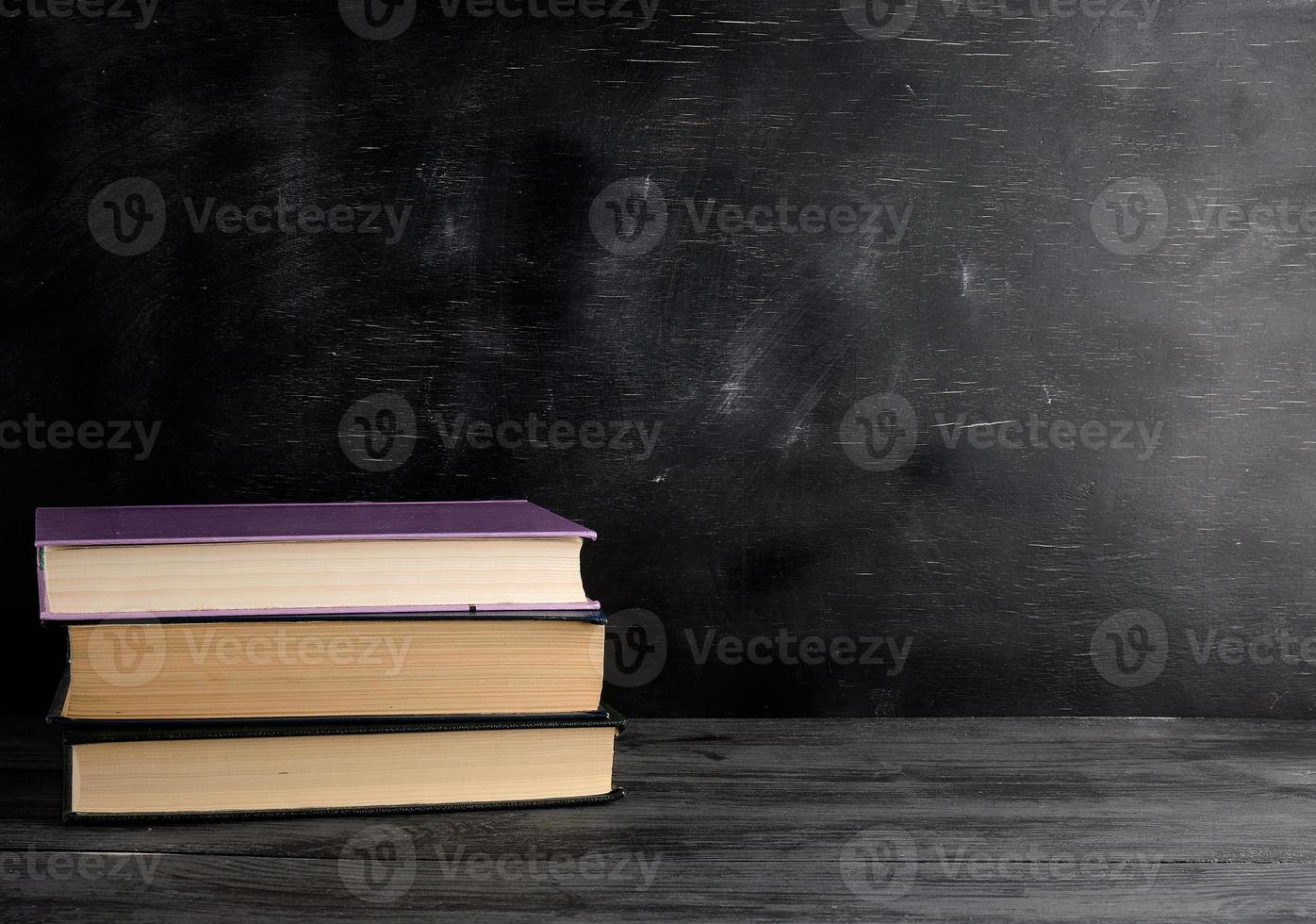 four closed books with yellow sheets on a black chalk board background photo