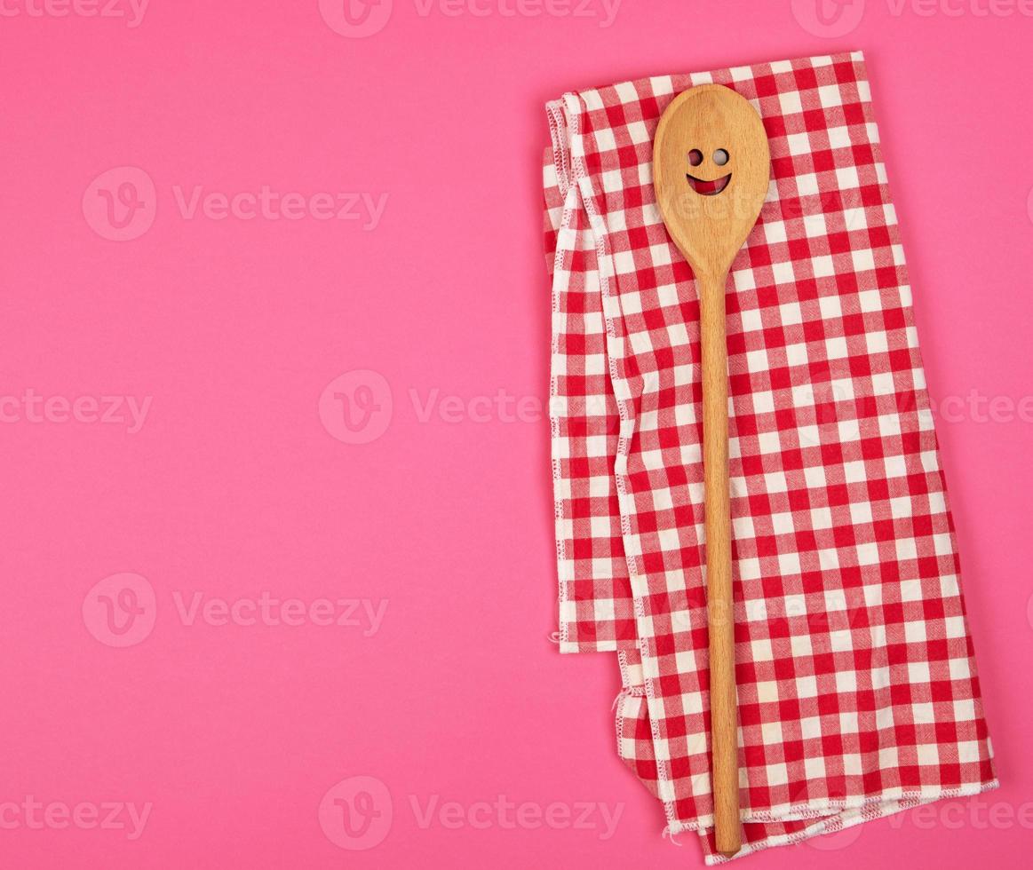 wooden spoon with a carved face on a red kitchen towel photo