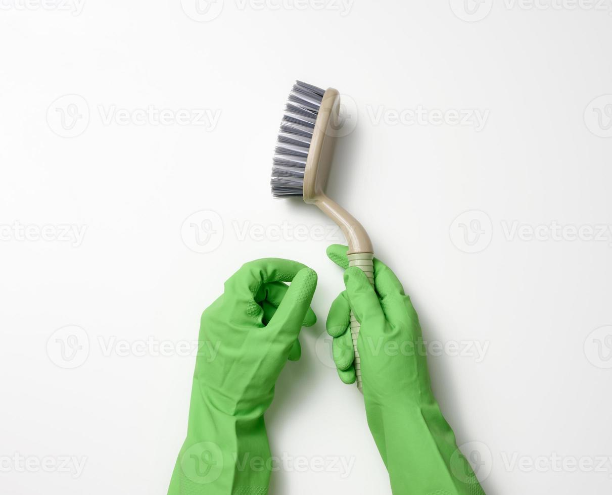 hand in a green rubber cleaning glove holds a plastic brush on a white background photo