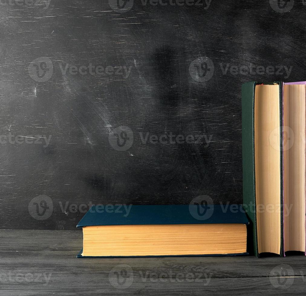 closed books with yellow sheets on a black chalk board background photo