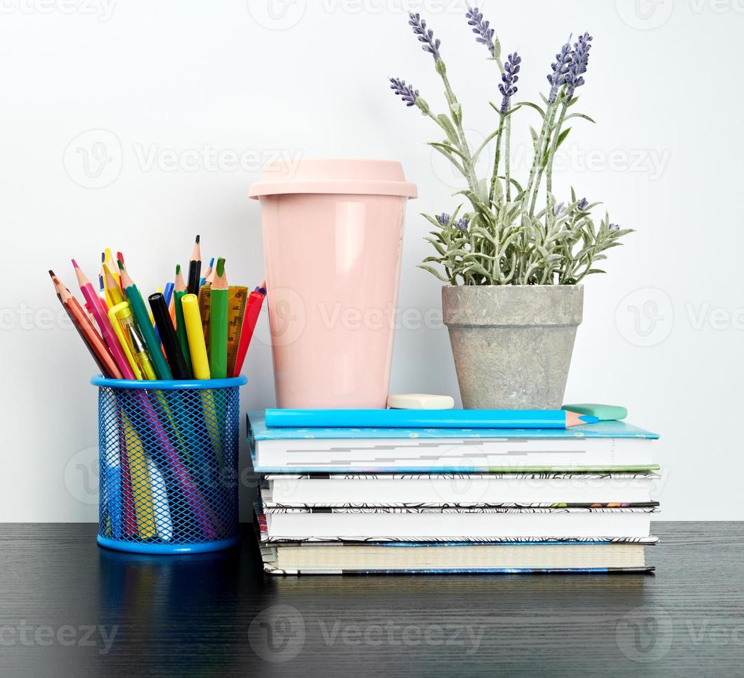 stack of spiral notebooks with white pages and ceramic pots with plants photo