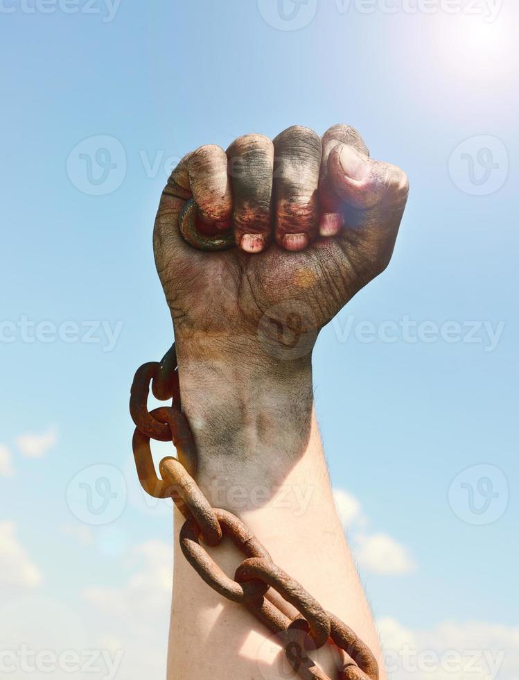 man's hand is encased in an iron rusty chain photo