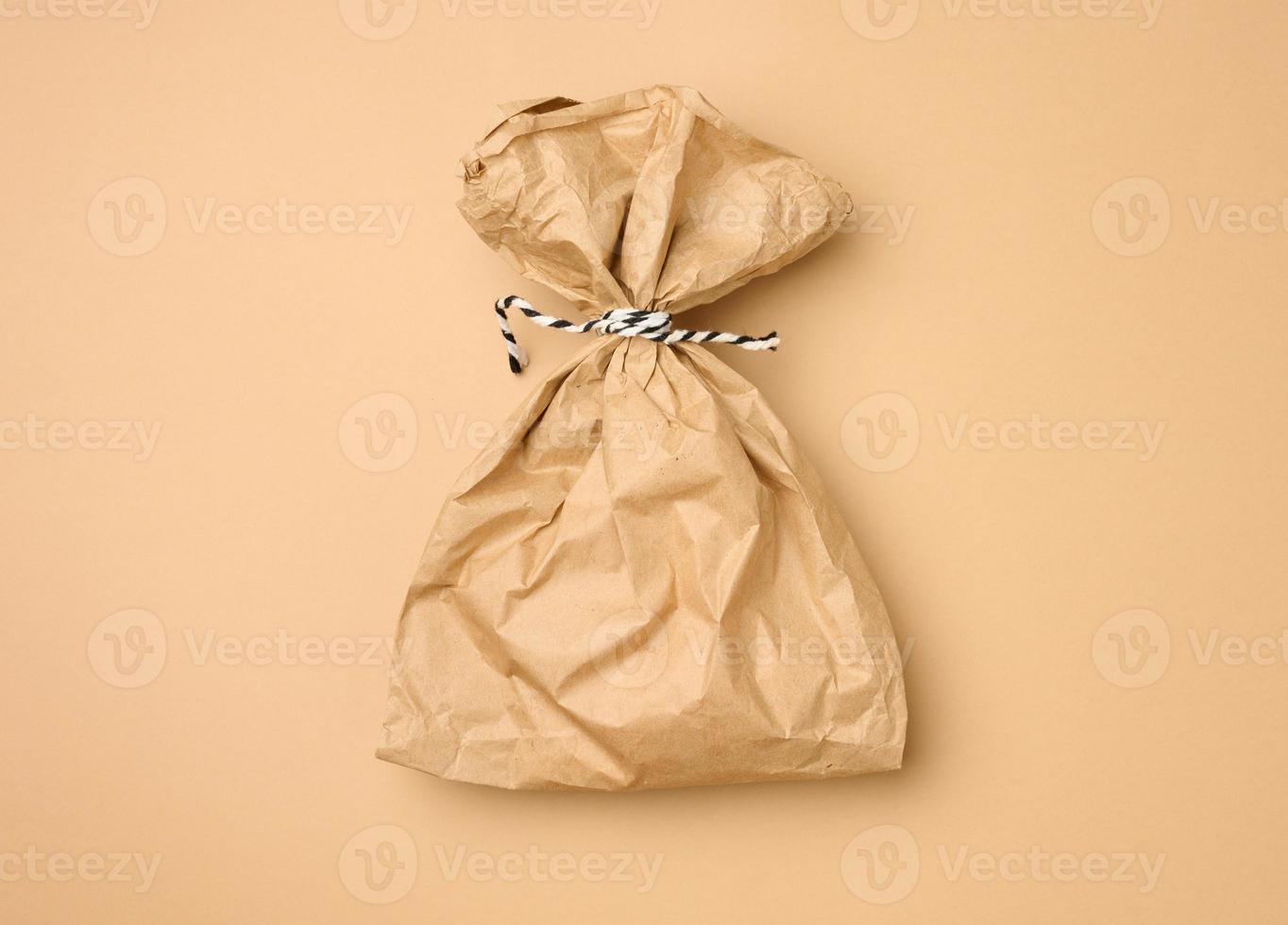 full brown paper disposable food bag on a beige background, concept of delivery and ordering photo
