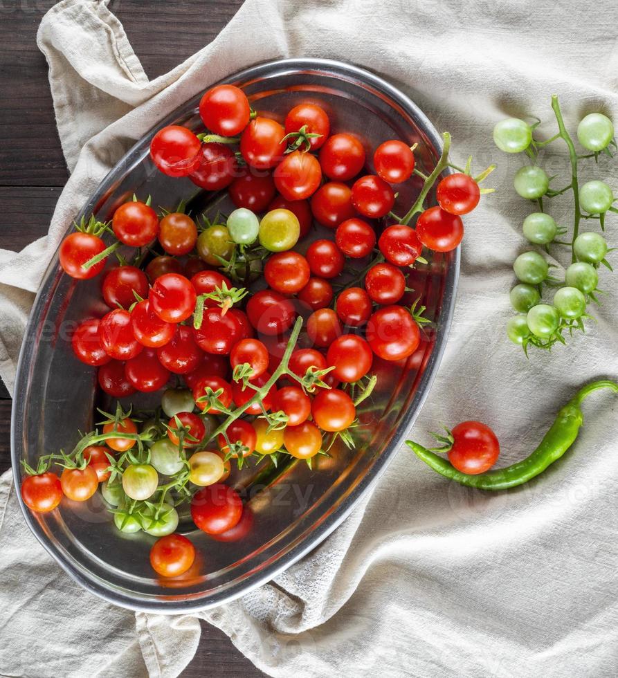 ripe red cherry tomatoes lie in a metal plate photo