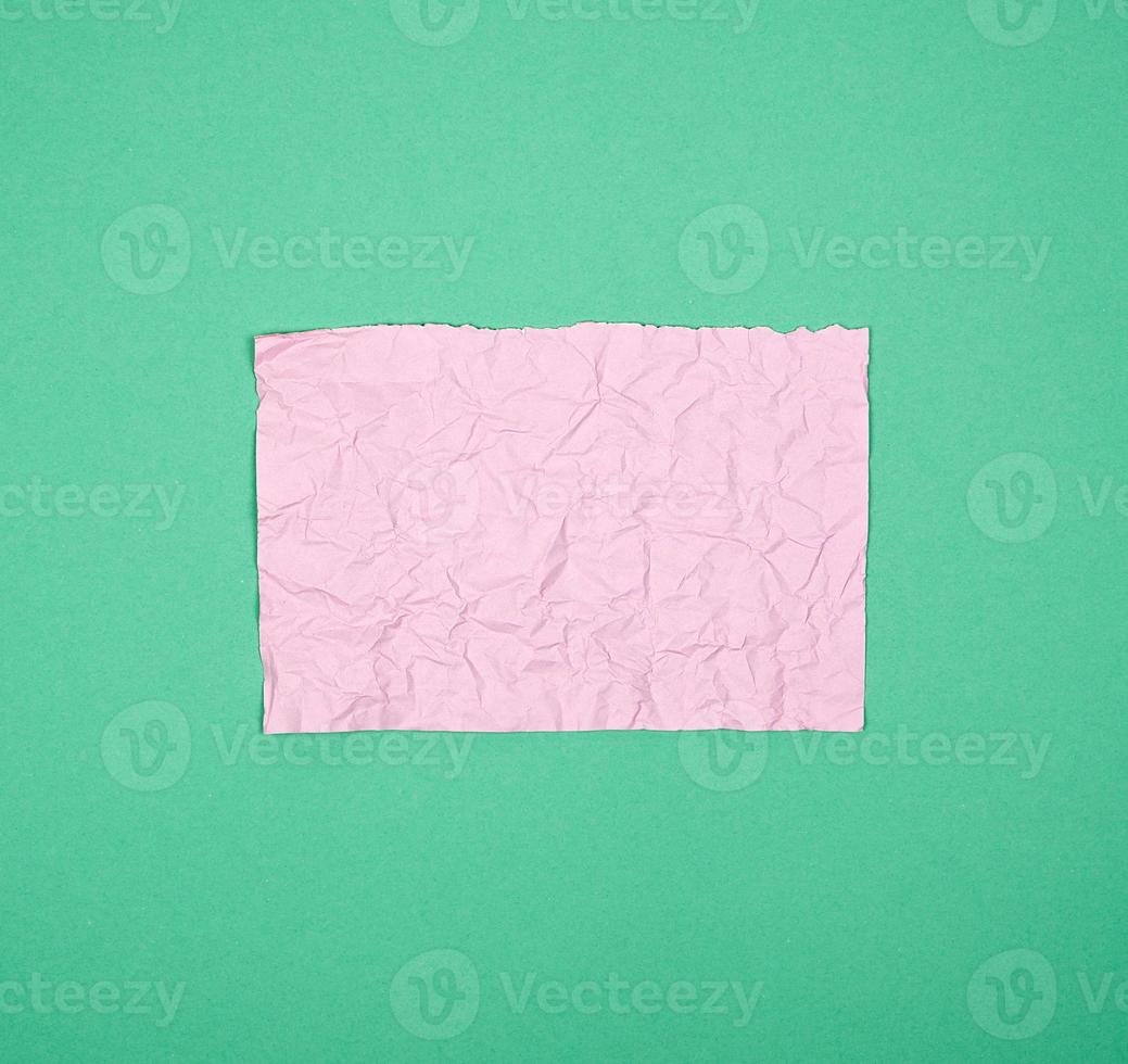empty crumpled pink rectangular sheet of paper on a green background photo